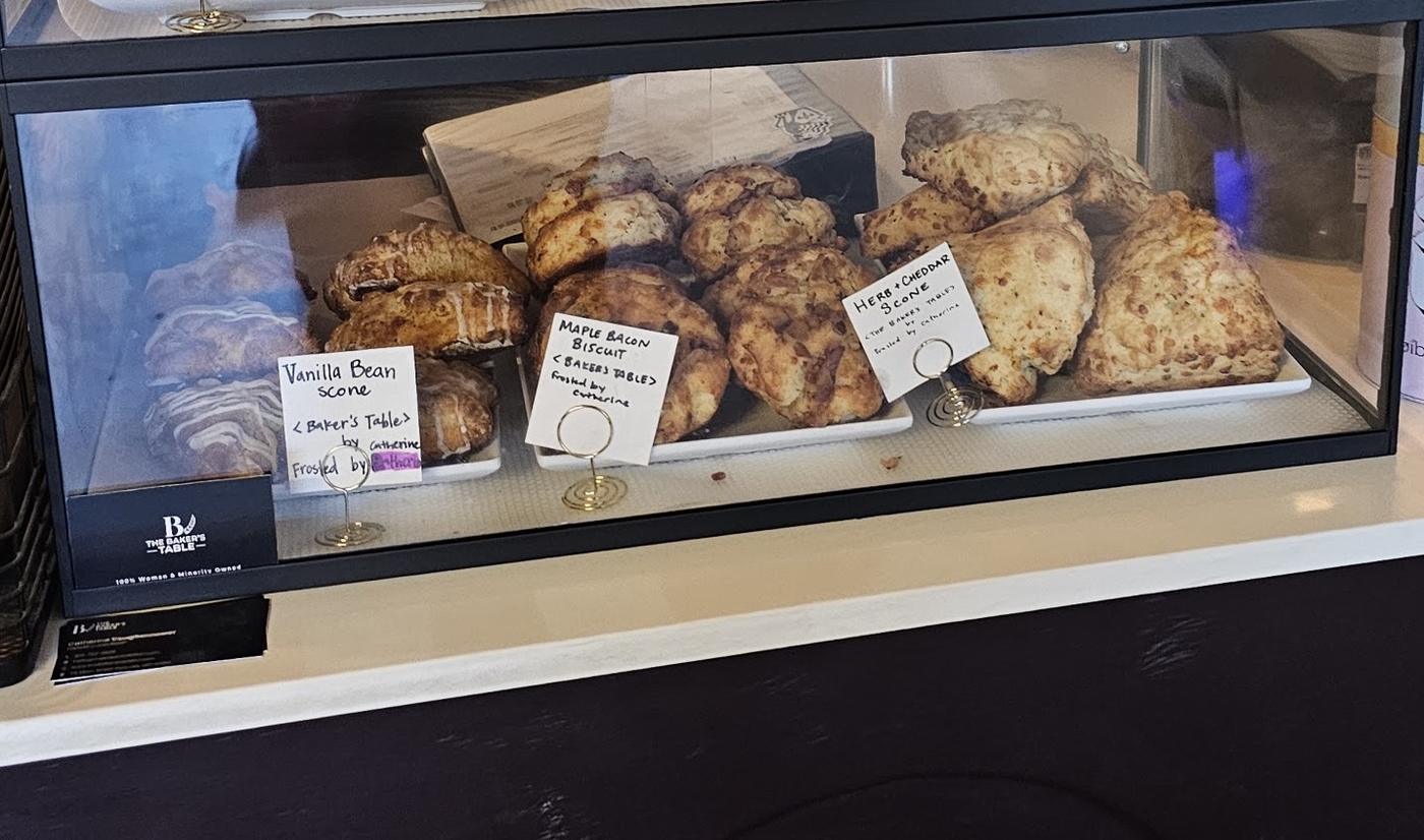 The pastry case: scones and biscuits on white plates with handwritten labels.